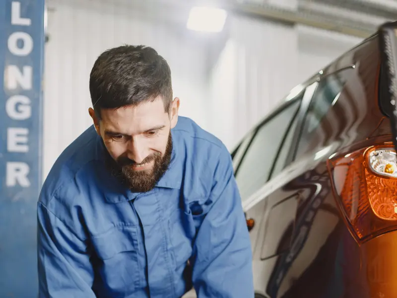 Mechanik w kombinezonie niesie oponę